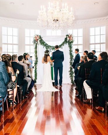 Bride and Groom exchanging wedding vows at a greenery arch at The Luxmore Estate