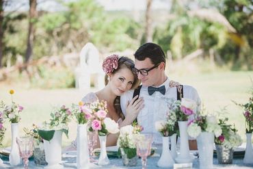 assorted white milk glass bud vases with pink and white wildflowers with bride and groom at table