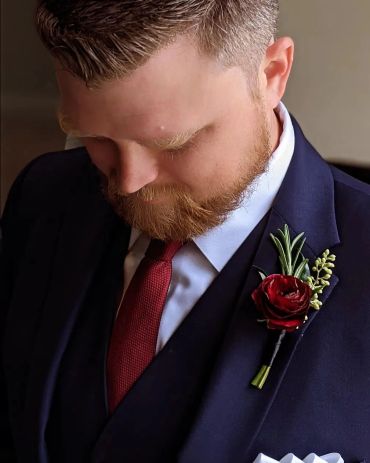 Man in navy suit with red tie looking down.