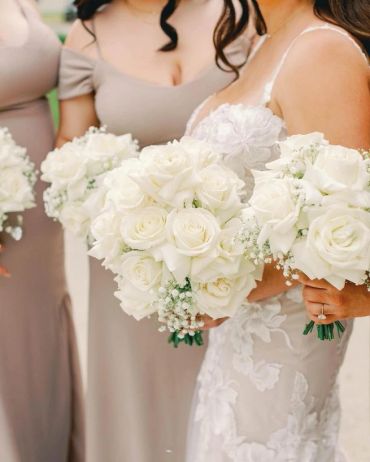 Bridesmaids and bride holding white rose bouquets.