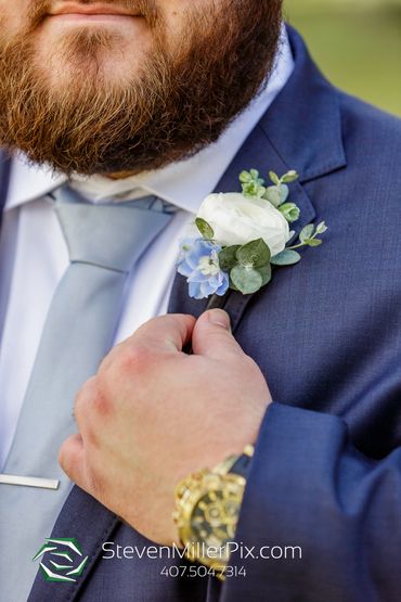 white ranunculus with light blue delphinium boutonniere