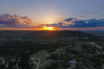 Sunset over a hilly landscape with scattered vegetation.