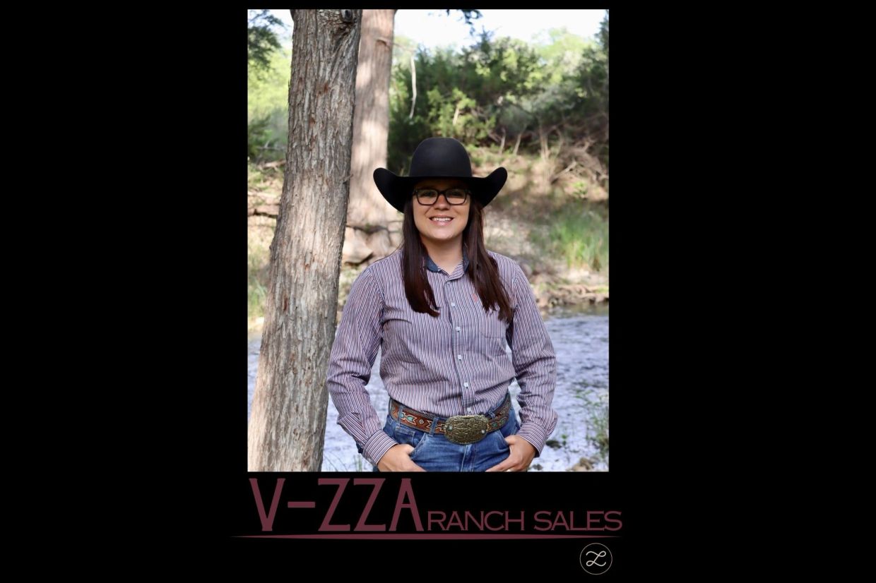 Woman in cowboy hat and glasses outdoors by a tree.