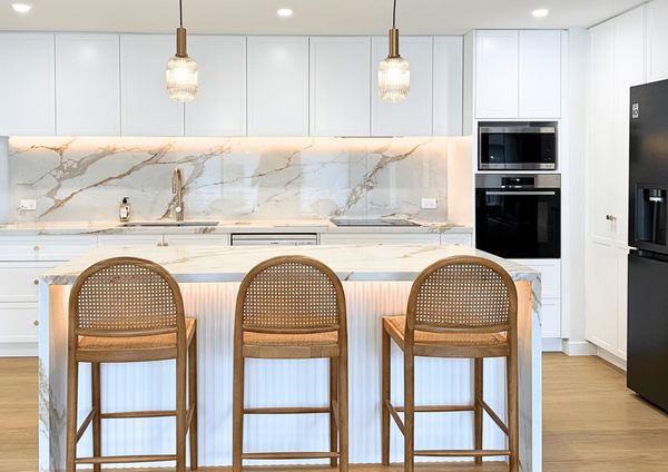 Modern kitchen with marble island and wooden stools.