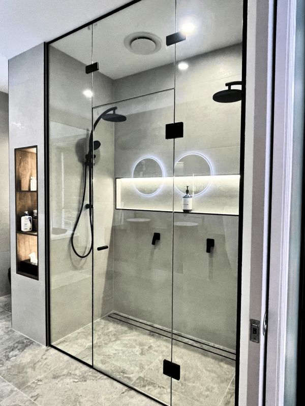 Modern glass-enclosed shower with black fixtures.