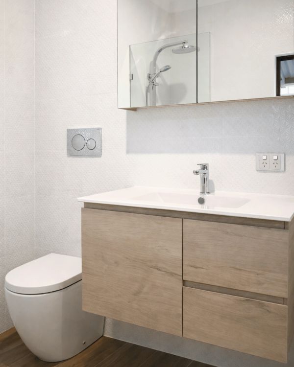 Minimalist bathroom with wooden vanity and white toilet.