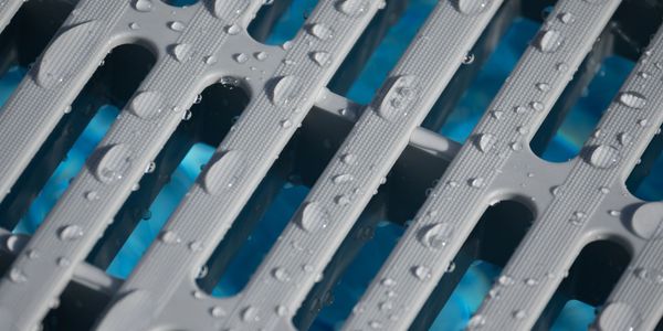 Close-up of water droplets on a plastic pool drain grate.