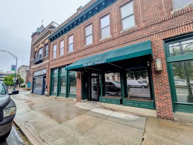 Brick building with green-trimmed windows and an awning reading 220 West Market.