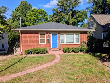Small brick house with a bright blue door and a curved walkway.