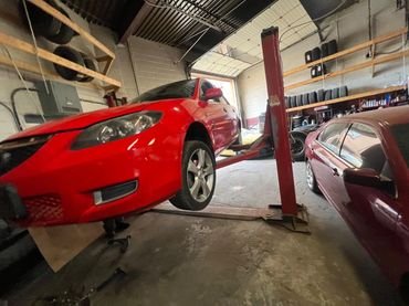 Red car lifted in a garage for maintenance.