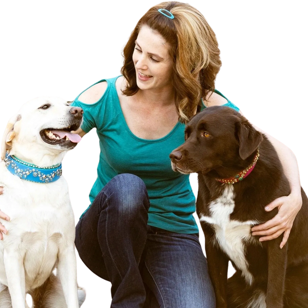 Woman happily posing with two dogs, one white and one brown.