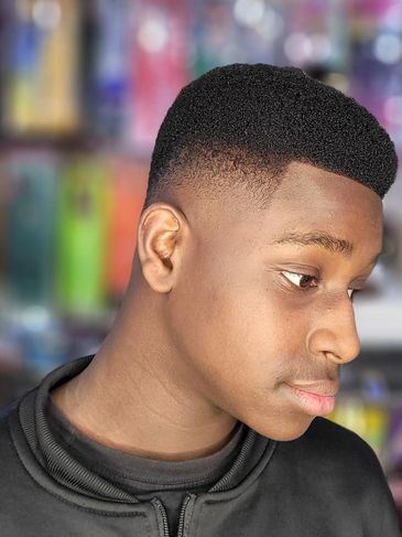 Young man with a fresh high-top fade haircut in a black jacket.