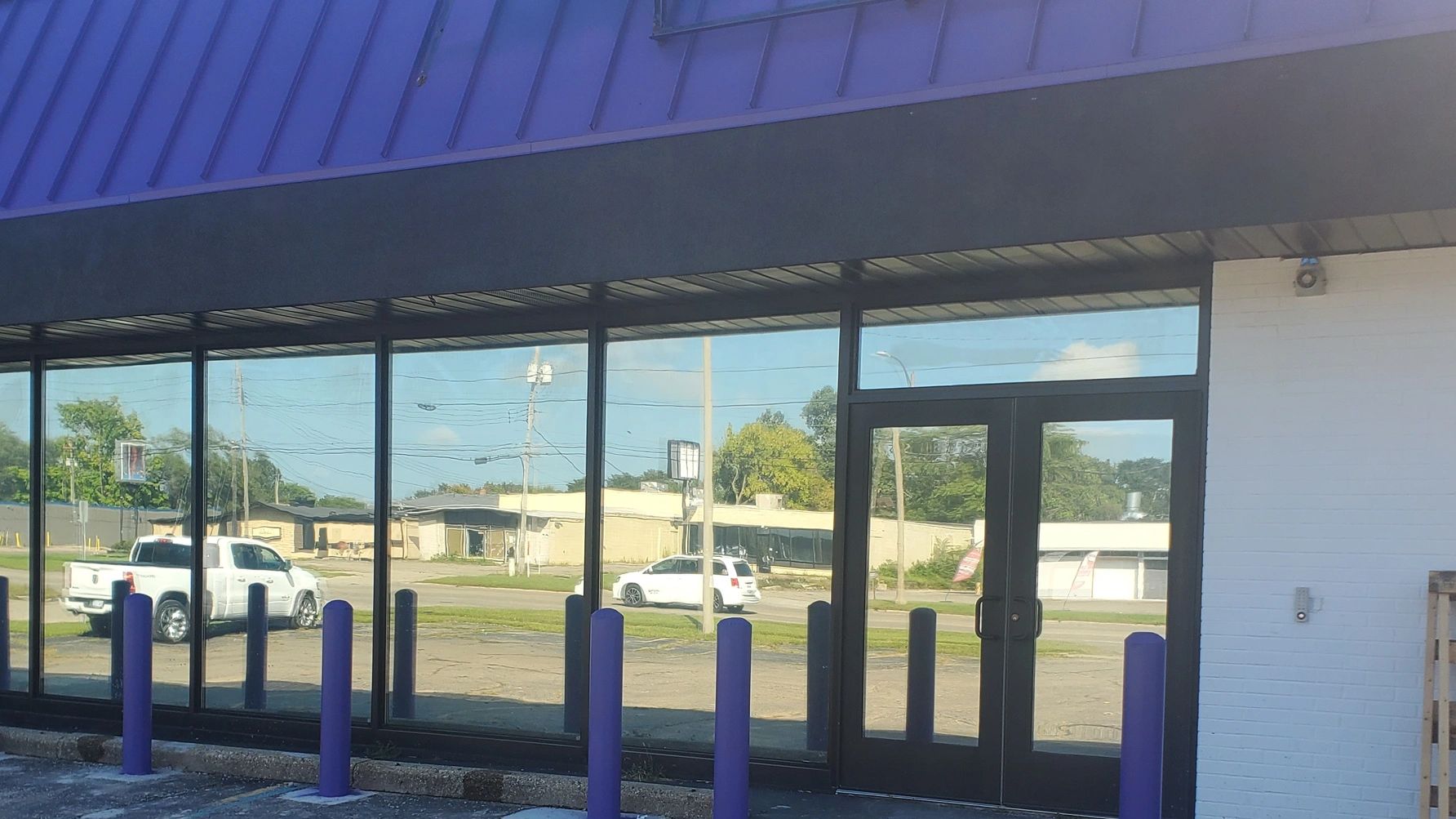 Storefront with glass windows and purple bollards.