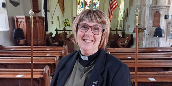 Smiling female clergy member inside a church.