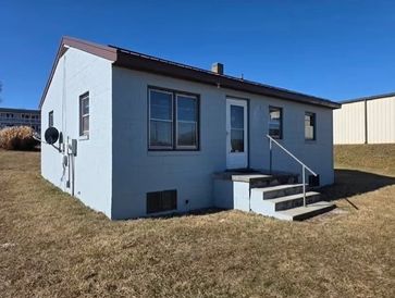 Small light blue house with stairs and railing under a clear blue sky.