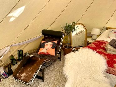 Cozy, stylish tent interior with a lounge chair and plush decor.