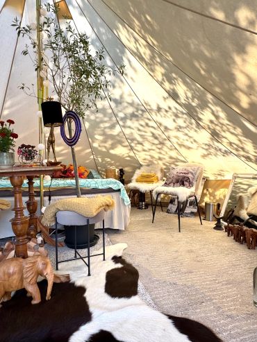 Cozy tent interior with rustic decor and soft furnishings.