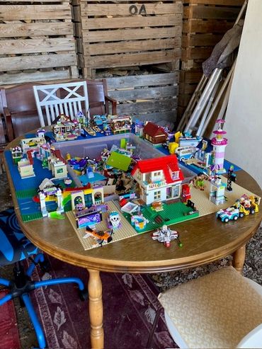 A detailed LEGO town setup on a wooden table with various buildings and vehicles.