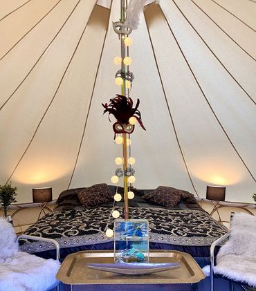 Cozy tent bedroom with decorated pole and warm lighting.