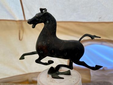 Bronze horse sculpture with detached legs on display.