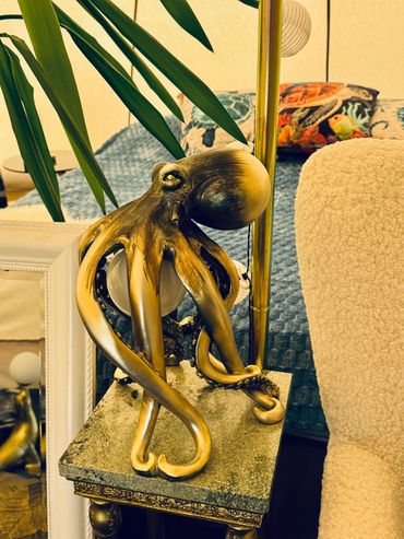 Golden octopus sculpture on a decorative table beside a cozy chair.