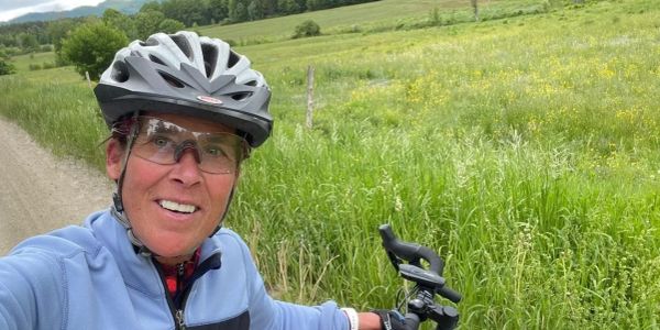 Person taking a selfie while biking in a lush green field.
