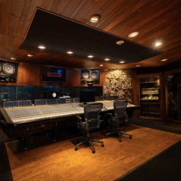 Professional recording studio control room with mixing console and ergonomic chairs.