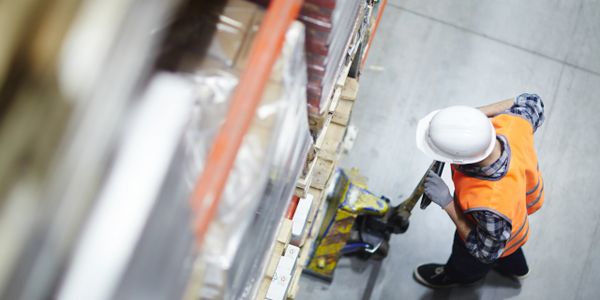 worker wearing protective gear while using pallet jack for pallet