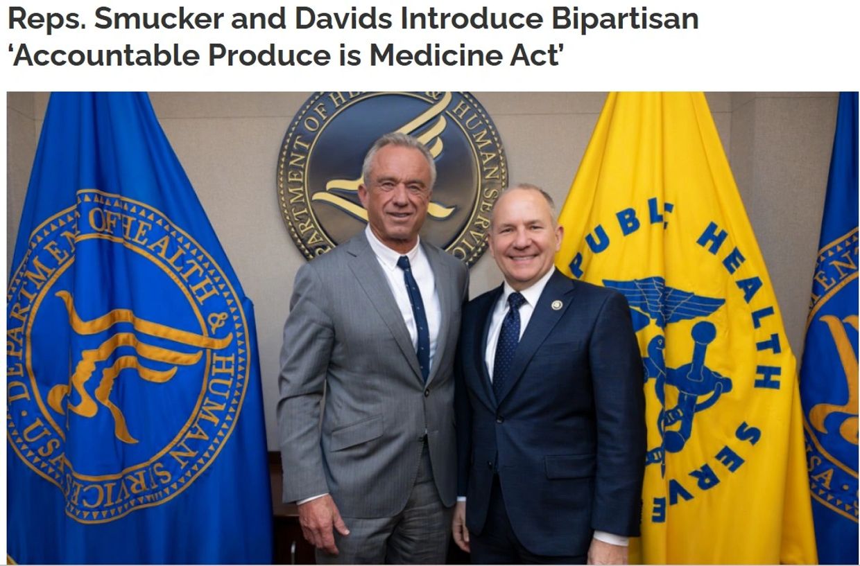 Two men in suits stand before Department of Health and Human Services flags.
