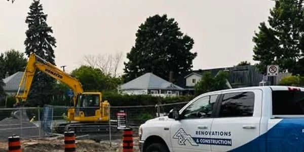 Construction site with an excavator and a company renovation truck.