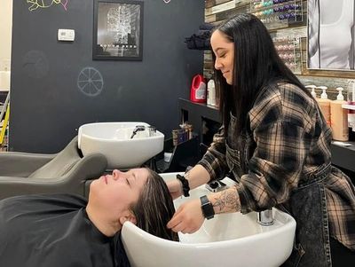 A woman washing another's hair at a salon sink.