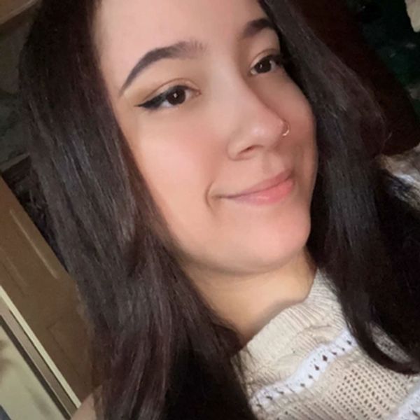 Young woman with long dark hair smiling gently, wearing a cream-colored sweater.