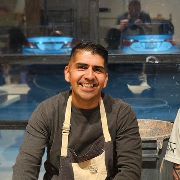 Man smiling while wearing an apron indoors.