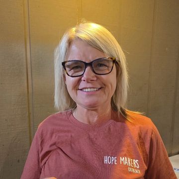 Smiling woman wearing glasses and a 'Hope Makers' t-shirt.