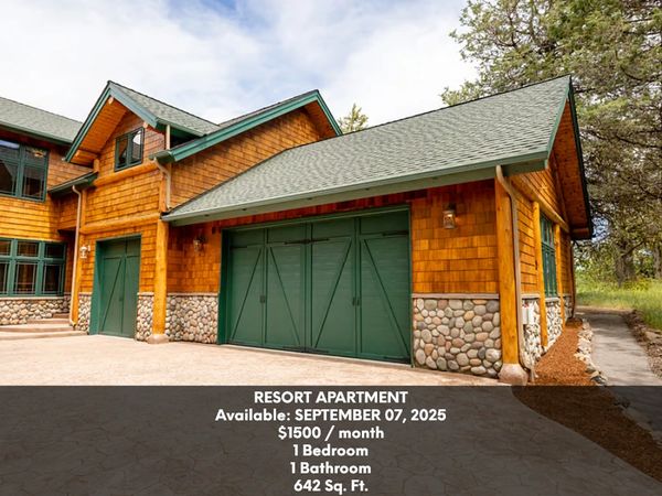 Wooden resort apartment with green garage doors and stone accents.