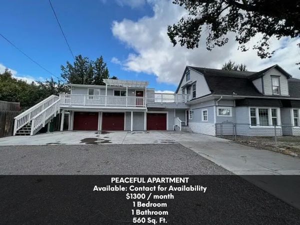 Apartment with white railings and red garage doors under a bright blue sky.