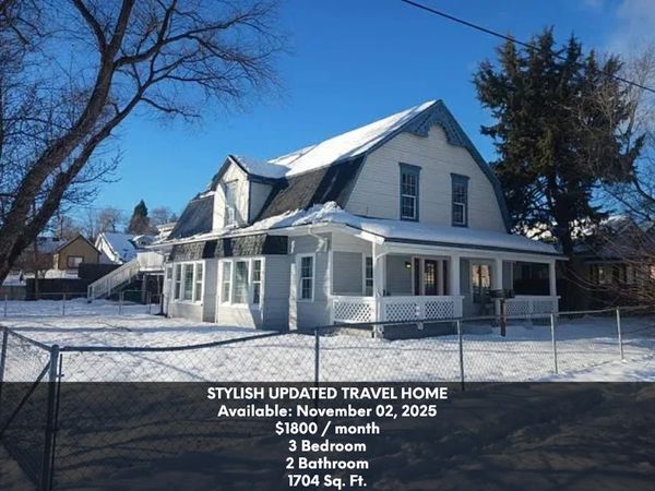 A stylish white travel home with snow-covered roof and yard, available for rent.