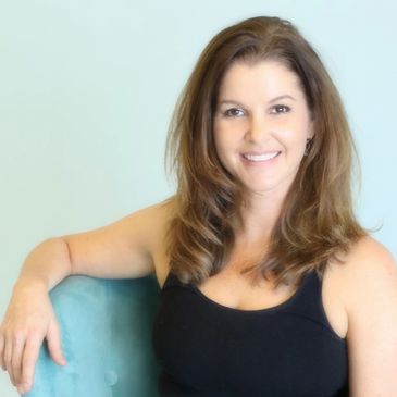 Smiling woman in black tank top sitting on a teal chair.