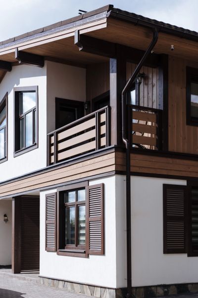 Modern two-story house with brown wooden accents and white walls.