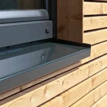 Modern window with a sleek metal sill on a wooden exterior wall.