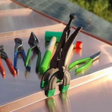 Various pliers and hand tools arranged on a reflective surface.