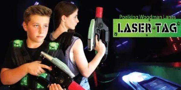 Two teens playing laser tag with guns and vests in a dark arena.