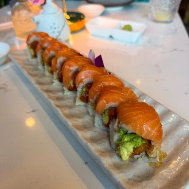 Fresh salmon sushi rolls neatly arranged on a ceramic platter.