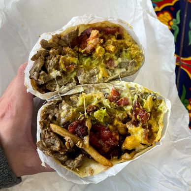 A close-up of a breakfast burrito filled with eggs, meat, cheese, and salsa.