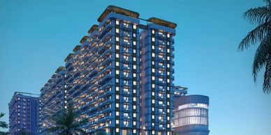 Modern high-rise residential buildings at dusk with illuminated windows and palm trees.