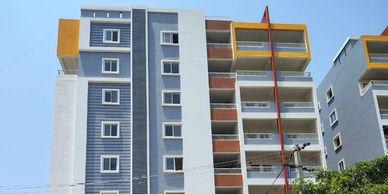 Modern multi-story residential building with blue, white, and yellow accents under a clear sky.