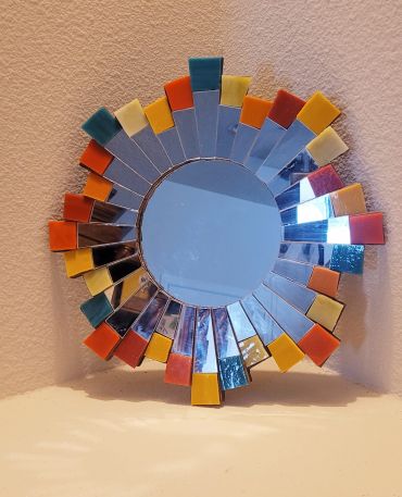 Decorative round mirror with colorful mosaic tiles.