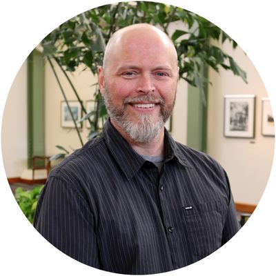 Confident man in a suit smiling while walking outdoors, showcasing fashion and style.