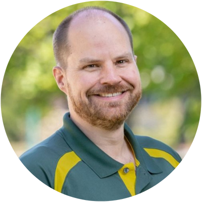 Confident man in a suit smiling while walking outdoors, showcasing fashion and style.
