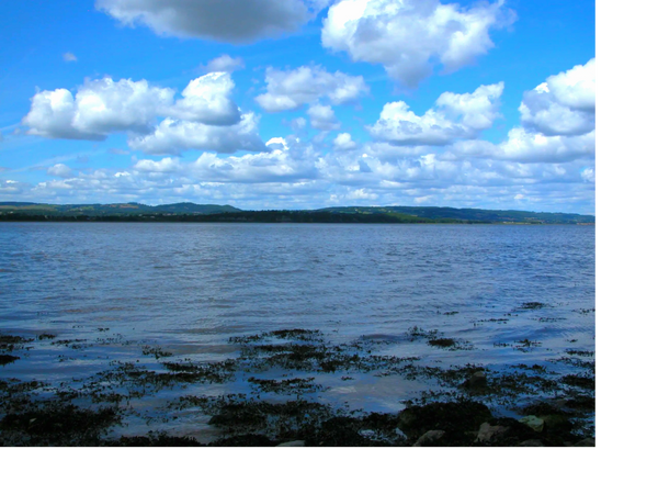 Calm water body under a partly cloudy sky with distant hills.